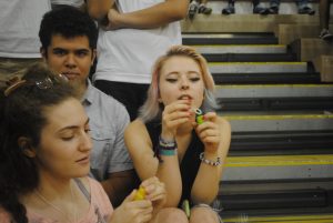 (Left to right) Seniors Lyna Bentahar, Leo Blondel and Lena Bradley sit on the bleachers and blows bubbles before the start of the pep rally.