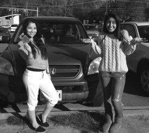 Sophomore Jacqueline Padilla (left) poses wit her parking permit hang tag in the RHS parking lot, while sophomore Livette Argueta (right) is empty handed.
