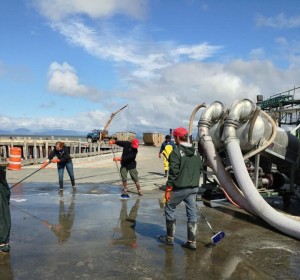 Fishery workers sweep excess water left on a dock in Ekuk, Alaska. A large percentage of the employees are college students, looking for high-paying summer jobs. --Courtesy of Chris Brown