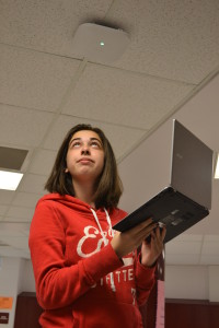 Junior Michaela Berger observes the white Wi-Fi router on a hallway ceiling. Berger of ten brings her laptop to school. --Elissa Britt