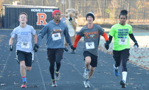 Senior Billy Kirk, Miguel Suero Nolasco, Manuel Suero and junior Adam Sarsony (third from left) hold hands as they prepare to finish the race. They created a four-way-tie for first place, the first ever in Rampace history. --Meklit Bekele