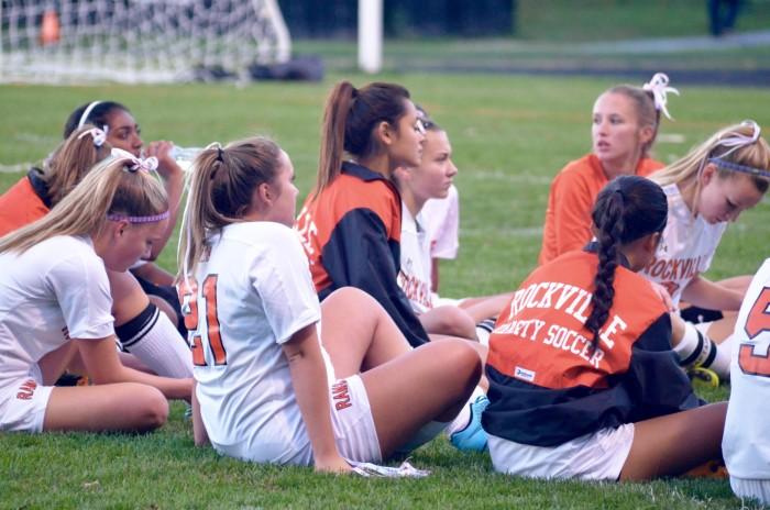 The girls varsity soccer team gathers to listen to their coach speak.