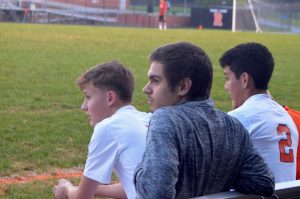 (Left to Right) Seniors Robin Clarke, Samuel Mejia, and Ronaldo Reyes watch the game form the sidelines.