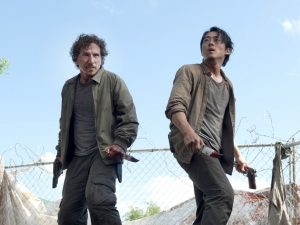 Nicholas (left) and Glenn (right) on top of a dumpster attempting to fend off a group of walkers. Courtesy of AMC.